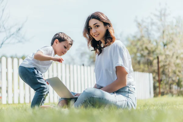 Messa a fuoco selettiva di felice freelance utilizzando computer portatile vicino carino figlio — Foto stock