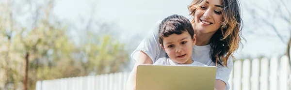 Horizontal concept of happy mother and son using laptop outside — Stock Photo