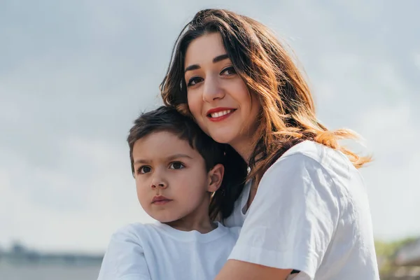 Donna allegra guardando la fotocamera e sorridendo vicino al figlio — Foto stock