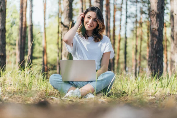 Foco seletivo de freelancer feliz sentado com laptop em madeiras — Fotografia de Stock