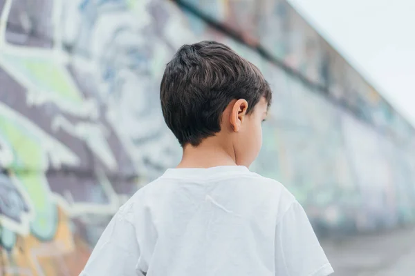 Vista posterior del niño en camiseta blanca de pie afuera - foto de stock