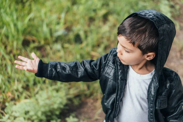High angle view of cute boy in black jacket standing with outstretched hand — Stock Photo