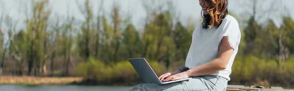 Récolte panoramique de freelance joyeux en utilisant un ordinateur portable tout en réseautant à l'extérieur — Photo de stock