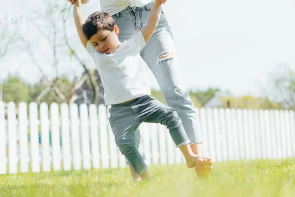 Messa a fuoco selettiva di carino ragazzo in piedi su piedi nudi di madre al di fuori — Foto stock