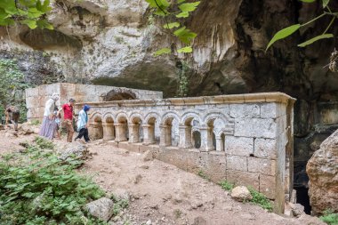 Mağara Silifke ilçesindeki Cennet Çöküğü doğru taş merdivenle kimliği belirsiz insanlar. Meryem Ana Kilisesi St. Paulus tarafından inşa arka planda olduğunu. Mersin Turkey.29 Ağustos 2017.