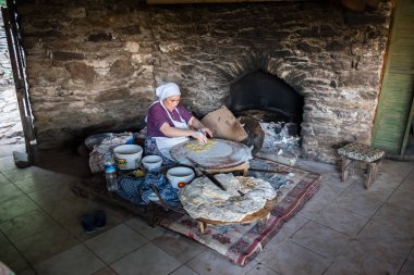Kimliği belirsiz bir kadın geleneksel Türk yemekleri Gozleme(pastries,pancake) Şirince Köyü, Selçuk, Izmir, Türkiye'de popüler bir hedef ocakta pişiriyor. 21 Ağustos 2017