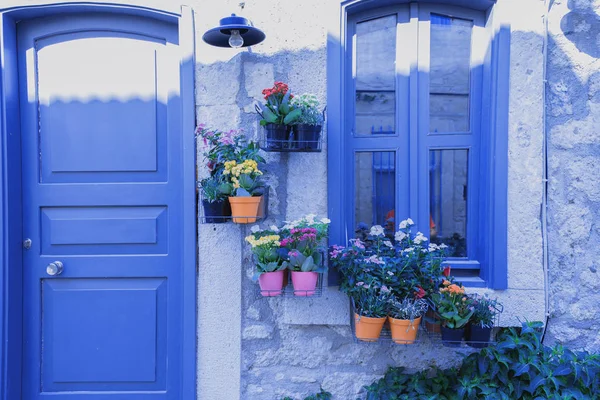 Retro View of purple door and window with hanging flowerpots and antique street lamp.