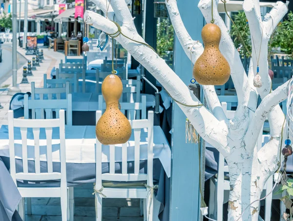 View of Bodrum streets,restaurant table and chairs with decorative calabash hanging on tree,Turkey.23 August 2017.