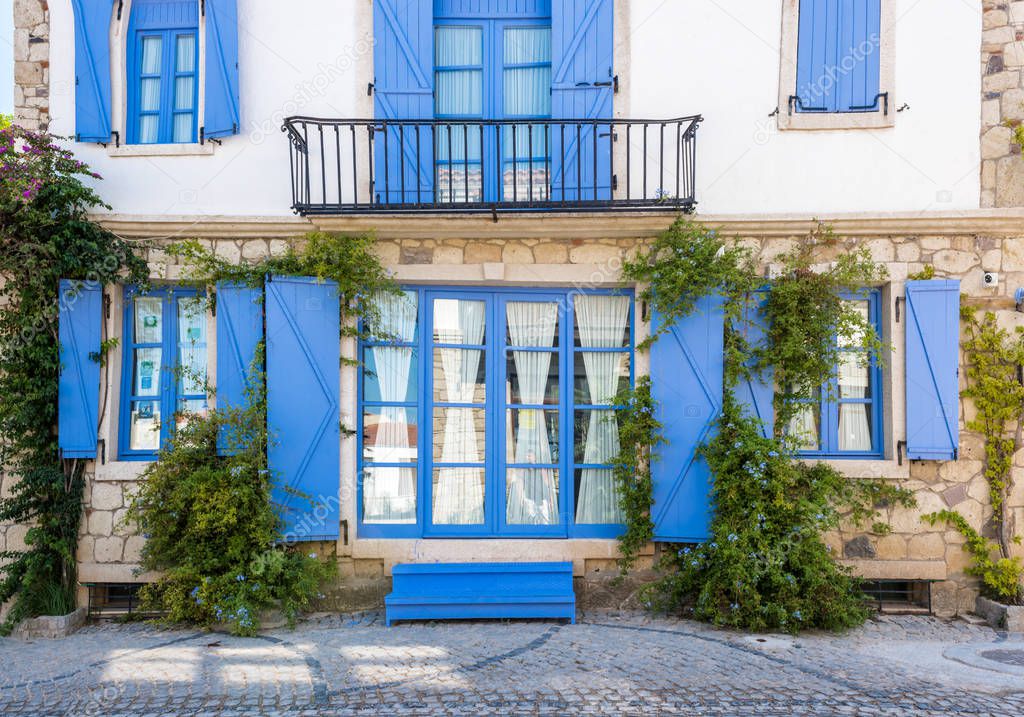 View of unidentified village house with blue windows and doors at Alacati charming Streets , a popular destination for traveling and vacation in Izmir,Turkey.