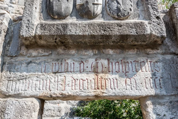 Cross and other signs carved into the wall of ancient Roman marble sculpture in Castle of St. Peter or Bodrum Castle, Turkey.