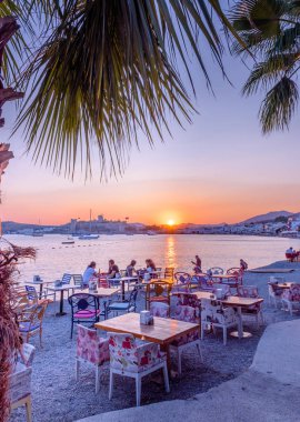 Kimliği belirsiz kişi plaj cafe ve yatlar ile Bodrum Deniz günbatımı manzarası ve Bodrum, Turkey.23 Ağustos 201 St. Peter Kalesi veya Bodrum Kalesi görünümünde tadını çıkarın