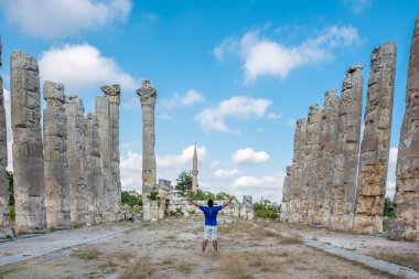 Genç adam t-shirt, silah ile açık açık zevk özgürlük Uzuncaburç, Silifke, Mersin, Türkiye'de bulunan antik antik kenti Zeus tapınağında yaymak.
