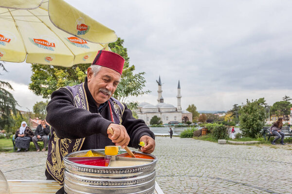 Unidentified man sells Ottoman Macun(Paste),soft, sweet and colorful Turkish toffee paste with Selimiye Mosque foreground.Edirne,Turkey.17 October 2015