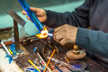 Bir cam konu el sanatları Fuarı'nda yapma el sanatları adamın ellerini. Alev alev yanan bir meşale ile erimiş cam çalışma cam maker. Yeni cam sanat parçası üzerinde lehim lâmbası alev, yakın çekim.