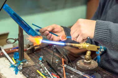 Bir cam konu el sanatları Fuarı'nda yapma el sanatları adamın ellerini. Alev alev yanan bir meşale ile erimiş cam çalışma cam maker. Yeni cam sanat parçası üzerinde lehim lâmbası alev, yakın çekim.