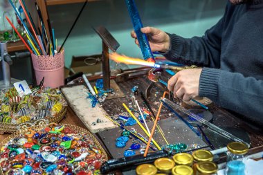 Bir cam konu el sanatları Fuarı'nda yapma el sanatları adamın ellerini. Alev alev yanan bir meşale ile erimiş cam çalışma cam maker. Yeni cam sanat parçası üzerinde lehim lâmbası alev, yakın çekim.