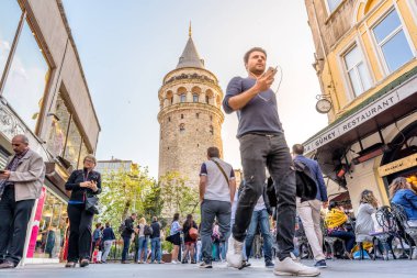 Kimliği belirsiz insanlar yürümek Galata Kulesi, Galata, Karaköy, Istanbul, Türkiye.29 bir Ortaçağ taş kule yakınındaki Nisan 2018