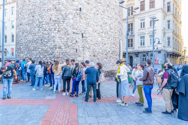 Неопознанные люди ждут в очереди, чтобы войти в Галатскую башню, средневековую каменную башню в Галате, Каракой, Стамбул, Турция .29 апреля 2018 года
