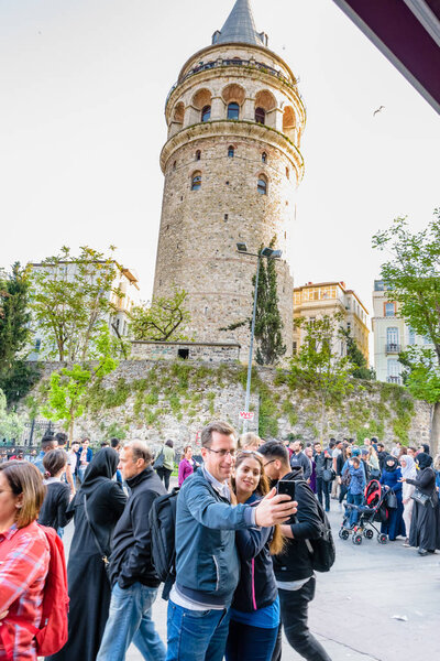 Неизвестные сфотографировались перед Галатской башней, средневековой каменной башней в Галате, Каракой, Стамбул, Турция. 29 апреля 2018 года
