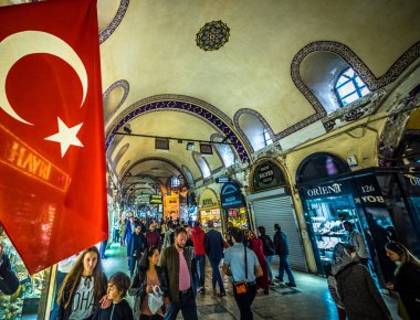Kimliği belirsiz turist ziyaret ve Kapalıçarşı Istanbul'da alışveriş. Türk bayrağı ile kapalı çarşı iç ön plan üzerinde. Istanbul, Turkey.April 17, 201