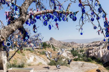 Mavi camdan Nazar Boncuk mavi gökyüzünde Güvercinlik Valley,Goreme,Turkey.Branches göz şeklinde muska ile Nazars, nazar, dekore edilmiş eski ağaç arka plan üzerinde ağaç ve masal bacaları üzerinde.