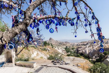 Mavi camdan Nazar Boncuk mavi gökyüzünde Güvercinlik Valley,Goreme,Turkey.Branches göz şeklinde muska ile Nazars, nazar, dekore edilmiş eski ağaç arka plan üzerinde ağaç ve masal bacaları üzerinde.