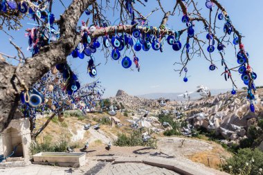 Mavi camdan Nazar Boncuk mavi gökyüzünde Güvercinlik Valley,Goreme,Turkey.Branches göz şeklinde muska ile Nazars, nazar, dekore edilmiş eski ağaç arka plan üzerinde ağaç ve masal bacaları üzerinde.