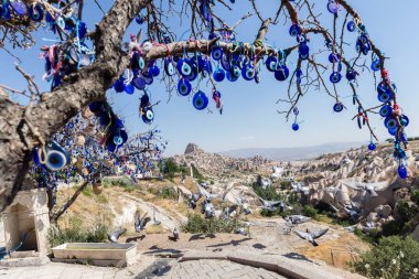 Mavi camdan Nazar Boncuk mavi gökyüzünde Güvercinlik Valley,Goreme,Turkey.Branches göz şeklinde muska ile Nazars, nazar, dekore edilmiş eski ağaç arka plan üzerinde ağaç ve masal bacaları üzerinde.