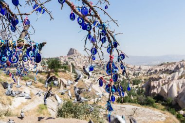 Mavi camdan Nazar Boncuk mavi gökyüzünde Güvercinlik Valley,Goreme,Turkey.Branches göz şeklinde muska ile Nazars, nazar, dekore edilmiş eski ağaç arka plan üzerinde ağaç ve masal bacaları üzerinde.
