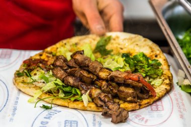 Adam el hazırlanıyor lezzetli karaciğer Türk şiş kebap ızgara silindir Mini değirmenler hizmet üzerinde.