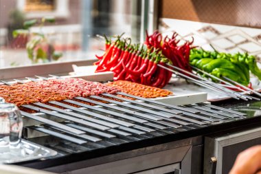 Birkaç Adana kebap şişleri pişmiş ve hizmet için bekleyen kaplı. Ham Türk geleneksel Sish kebab, et, karaciğer, sığır eti, et bir restoranda aşçı için hazır. Arka plan üzerinde ızgara için bile delip yeşil ve kırmızı biber.