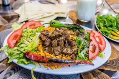 Türk şiş kebap dilimlenmiş lavaş, maydanoz, soğan, marul, domates, ızgara biber, Karışık turşu ve ayran ile beyaz bir tabakta servis ızgara lezzetli karaciğer ayrıntılı bir görünümünü kapat.