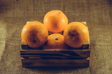 Olgun turuncu meyve eski yanık ahşap sandık veya kutu tutuyordu arka plan ile. Vintage ve retro etkisi eklendi.