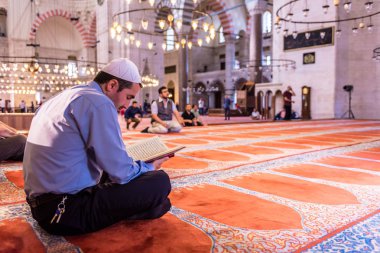 Turkish man reading kuran(Koran) in Suleymaniye mosque on ramadan feast month.ISTANBUL, TURKEY JUNE 04, 2017 clipart
