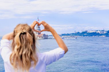 Güzel kadın Gezgin görünümünü Maidens Tower, Istanbul, Türkiye'de popüler bir hedef kalp şekli elle yapar