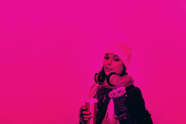 Duotone of beautiful woman in beanie hat with takeaway coffee and headphones.Millennial young woman in fall relaxing, drinking coffee.