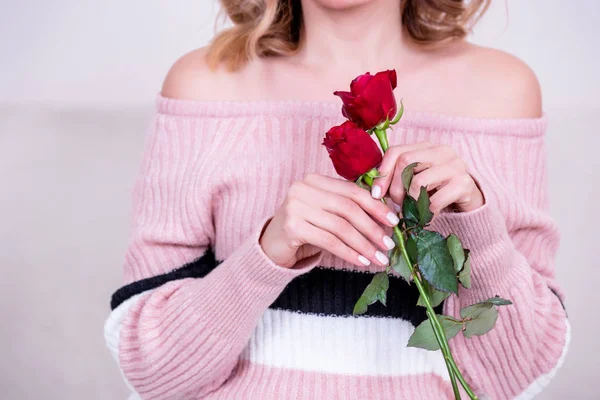 Çekici güzel model kadın beyaz arka planda izole edilmiş iki kırmızı gül tutuyor. Fotoğraf kavramı.