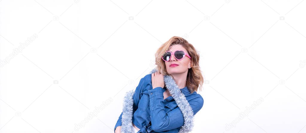 Portrait of young blonde attractive woman in silver tinsel and pink heart shape sunglasses has fun isolated on white background. Merry Christmas and New Year theme. Party time 