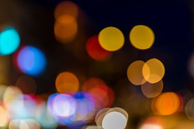 Odaklanmamış ve bulanık bokeh: Renkli bulanık araba farları ve karanlıkta parlayan trafik ışıkları büyülü bir atmosfer yaratıyor