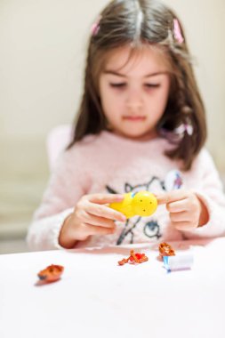 Küçük şirin kız çikolata yumurta ile tablo içinde oyuncak hom otururken açar