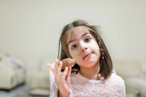 Маленькая Милая Девочка Ест Шоколадку Забавным Лицом Глядя Камеру — стоковое фото