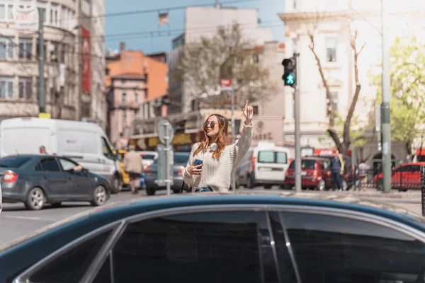 Mooie vrouw zoekt een taxi op straat — Stockfoto