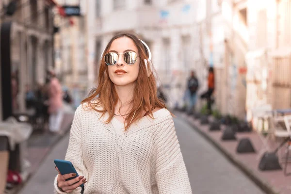 Vacker ung flicka lyssnar musik medan du går — Stockfoto
