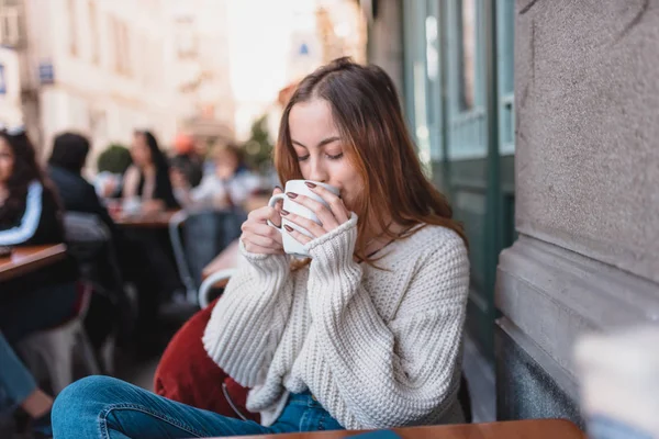 Красивая девушка в кафе на открытом воздухе пьет кофе — стоковое фото