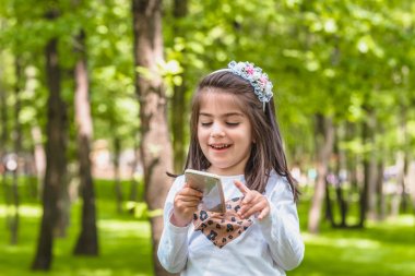 rahat giysiler içinde sevimli küçük kız cep telefonu tutar