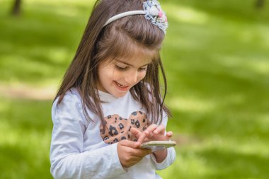 rahat giysiler içinde sevimli küçük kız cep telefonu tutar