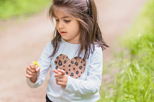 Mignonne petite fille cueille fleur sauvage à prairie — Photo