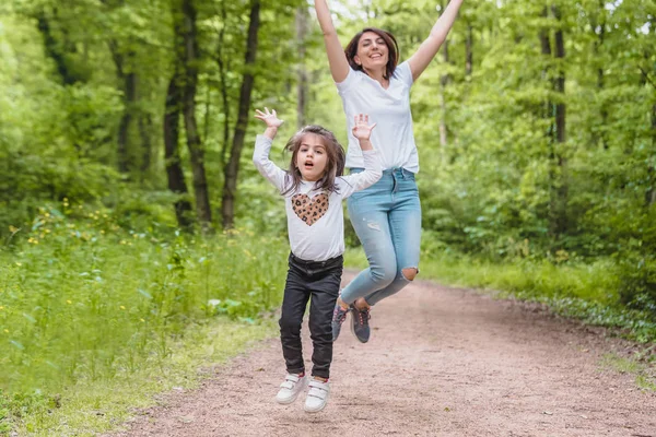 Jovem mãe e menina pular juntos . — Fotografia de Stock