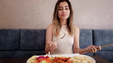 Yavaş hareket: güzel genç kız oturma sırasında bir restoran veya kafede büyük bir zevk ile tavuk yemi yiyor. Gıda konsepti