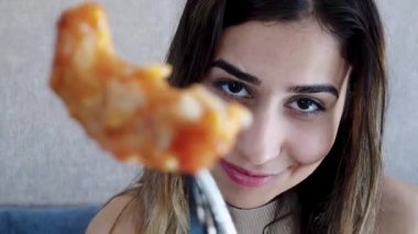 Yavaş hareket: güzel genç kız oturma sırasında bir restoran veya kafede büyük bir zevk ile çatal tavuk parçası gıda gösterir. Gıda konsepti